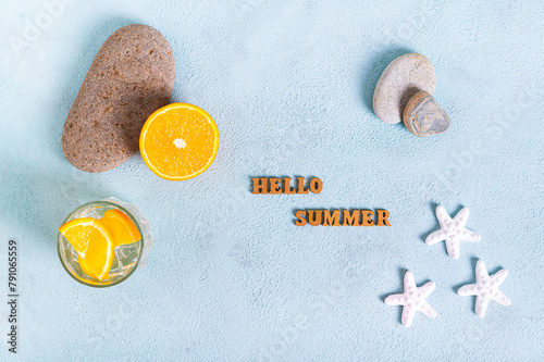 Concept hello summer text, cocktail, orange, stones and starfish on blue top view