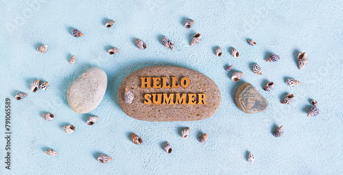 Concept hello summer text on stone surrounded by seashells on blue background top view web banner