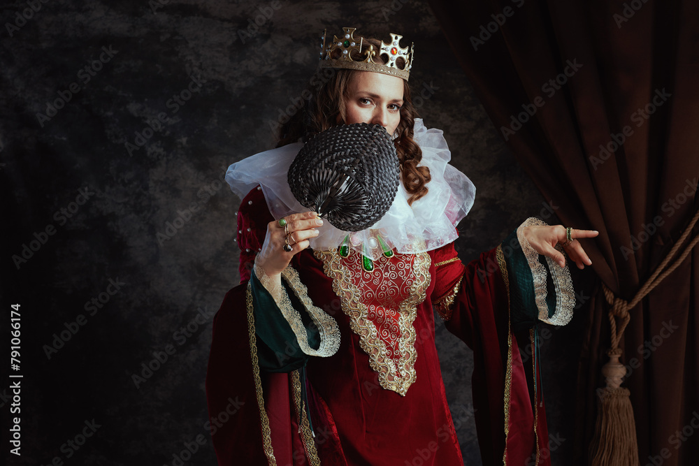 Fototapeta premium medieval queen in red dress with fan, white collar and crown
