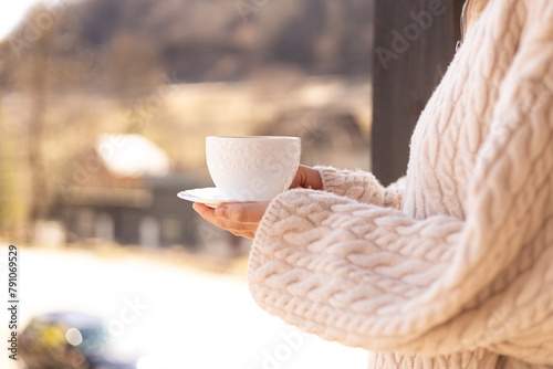 female hands in a sweater hold a cup of coffee