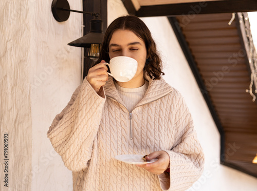girl in a sweater drinks a cup of coffee