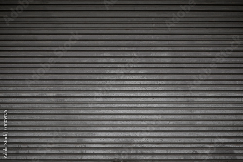 Front view of an old and weathered closed security roller door (or roller shutter, sectional overhead door, roll up or rolling garage door). Abstract full frame garage door background in black & white
