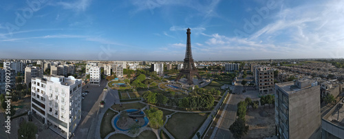 An aerial 180-degree panorama of the Eiffel Tower's replica among residential towers and buildings, located in Lahore's Bahria Town. 