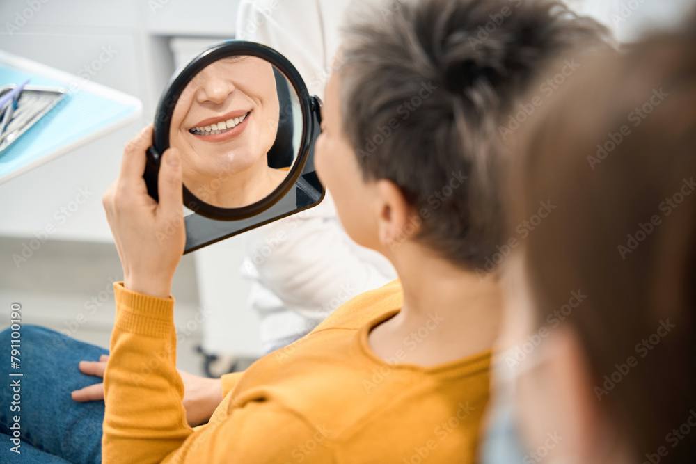 Woman client looking at her healthy, clean and whitened teeth