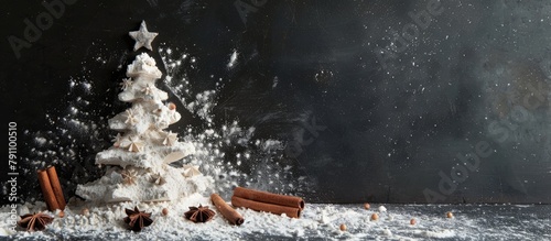 A Christmas tree crafted out of flour set against a black backdrop adorned with anise stars and cinnamon sticks.