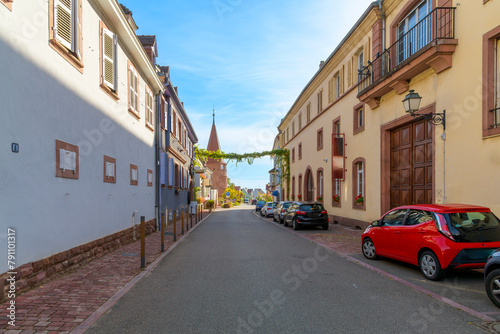 Fototapeta Naklejka Na Ścianę i Meble -  A picturesque street in the small town of Ammerschwihr, France, part of the Alsatian wine route of wine producing villages, with the Prankster Tower in view at the end of the street.