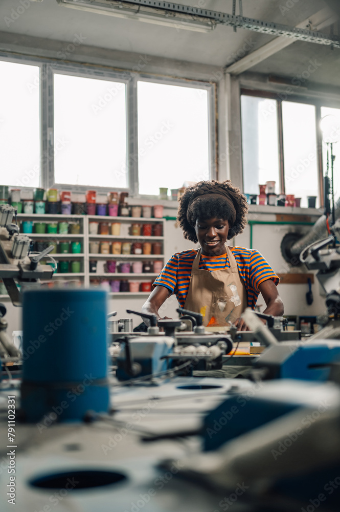 Interracial printing worker is silkscreen printing at printing workshop