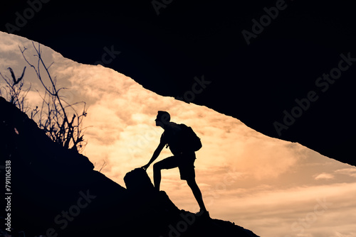 Male hiker climbing up mountain cliff, never give up, people perseverance, determination ,achieving goals, taking risk 