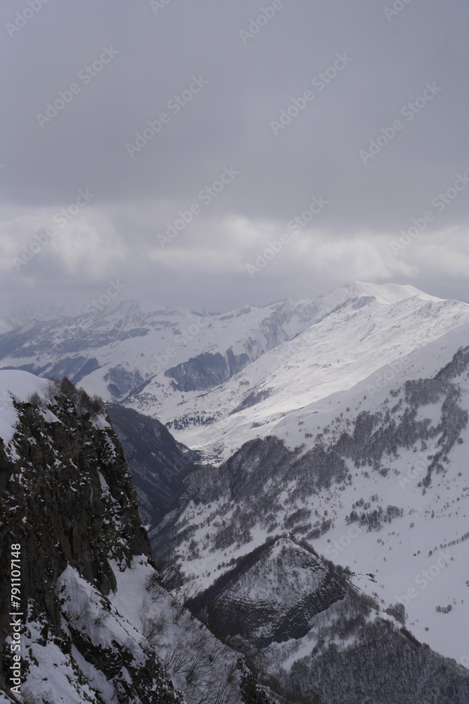 The snow-covered peaks of the mountain range under a sky with clouds, Devil's Valley in the Caucasus mountains, Gudauri, Georgian Military Highway, Georgia