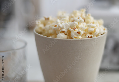 Off white ceramics cup filled with fresh popcorn. Very selective focus
