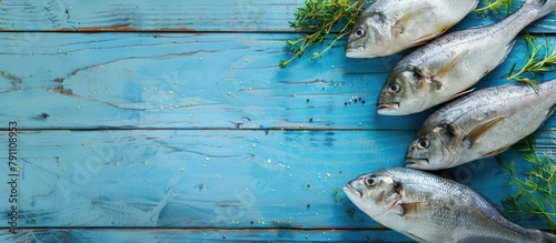 Assortment of fresh fish and herbs on a blue wooden backdrop with room for text.