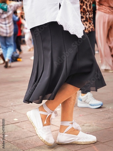 Woman wearing traditional shoes and skirt dancing the sardana, a Catalan folk dance.