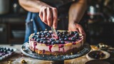 Person slicing blueberry cheesecake on wooden countertop