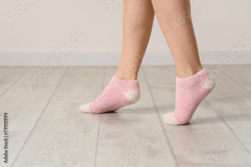 Woman in socks on laminate floor near light wall, closeup