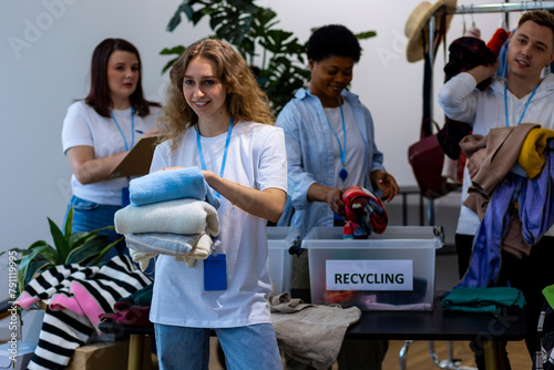 Concept of sustainable living, conscious consumption, eco friendly lifestyle. Young woman brings clothes for charity, donation, reuse, recycling. Volunteers at work accepting, sorting textile