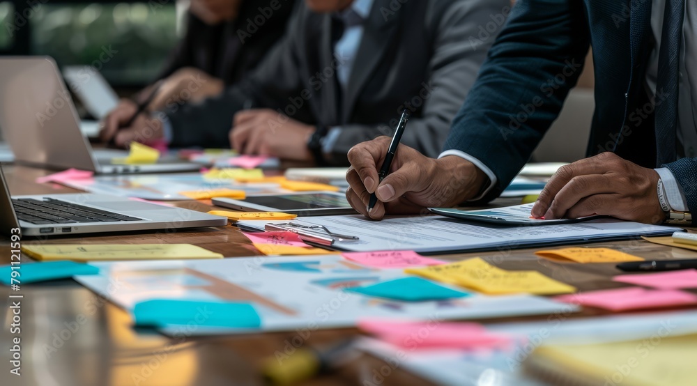 Close up of business people team working together at the office table with documents, laptop and sticky notes.