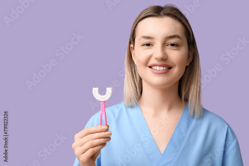 Female dentist with child toothbrush on lilac background, closeup