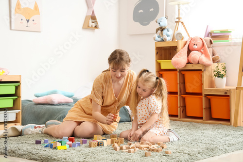 Nanny and little girl playing with cubes at home