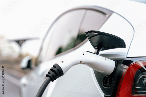 Closeup EV charger handle plugged in or connect to electric car, recharging EV car battery with alternative and sustainable energy with zero CO2 emission for clean environment. Perpetual