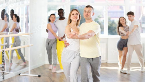 Graceful young girl and boy training waltz dance poses in dancehall during workout session