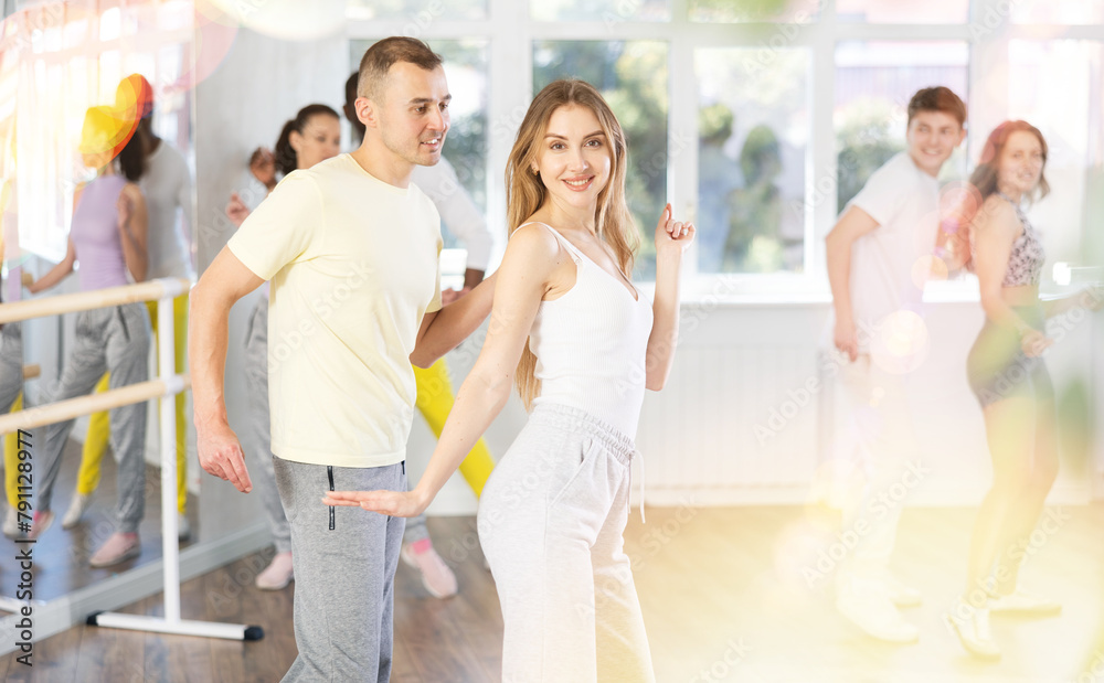 Fototapeta premium Slim young man and woman practicing active dance in training hall during group dancing classes