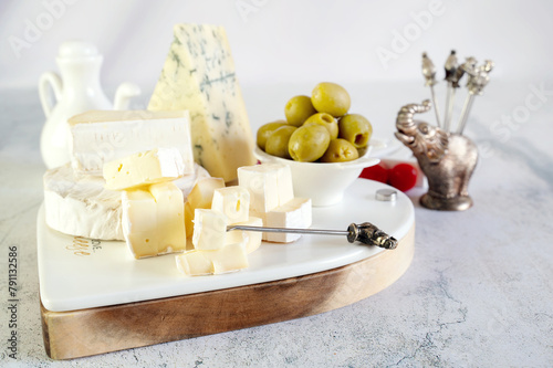 Canvas-taulu White soft cheeses with mold Camembert, Dorblu and Brice with olives and tomatoes on a marble background