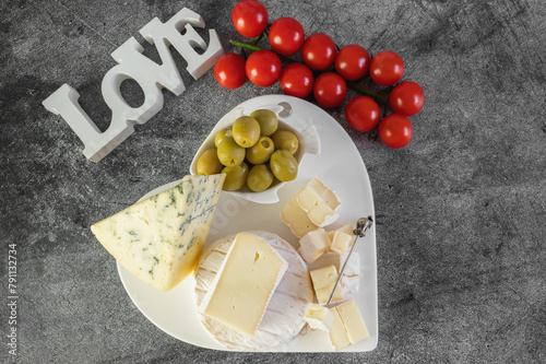
White soft cheeses with mold Camembert, Dorblu and Brice with olives and tomatoes on a marble background. photo