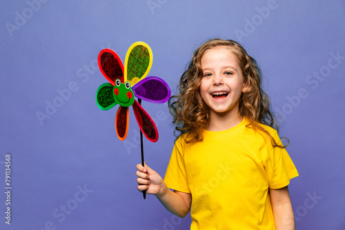 Photo of little cheerful girl happy positive smile hold paper toy windmill isolated over lilac color background. Summer vibes concept
