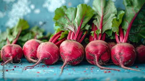  A collection of radishes atop a blue table, near a verdant, leafy plant