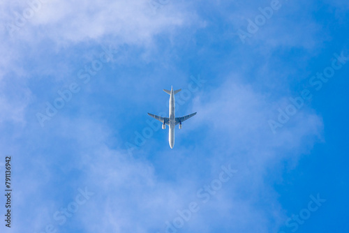 Uprisen angle view of the airplane flying in the air after take off with blue sky and white clouds, Under view of aircraft above in the sky before landing, Air transportation background.