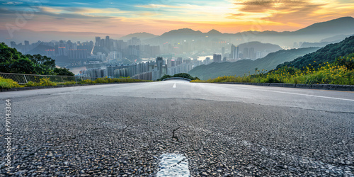 Asphalt road and mountain with city skyline scenery.