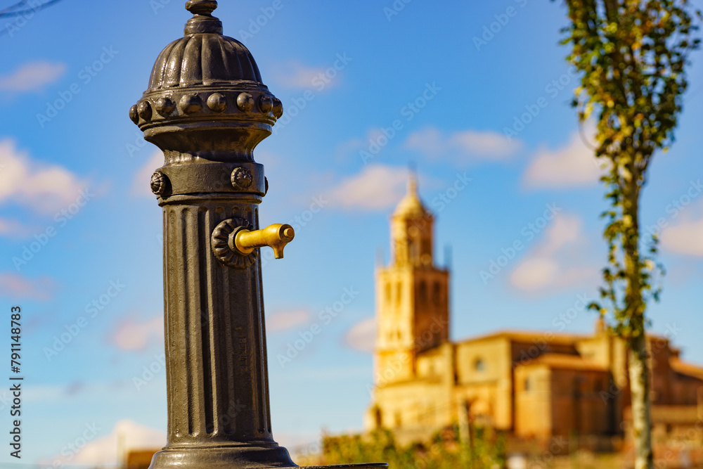 Old hydrant and church in town Santa Maria del Campo, Spain.
