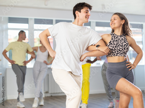 Slim young man and woman practicing national dance in training hall during group dancing classes © JackF
