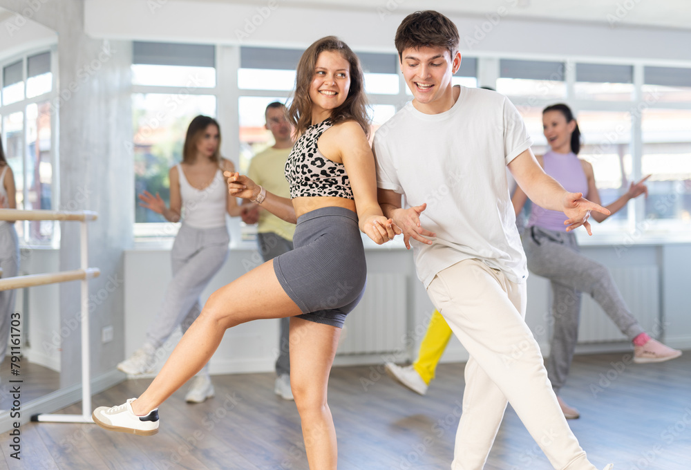 Fototapeta premium Couple of young guy and young woman dancing twist in studio