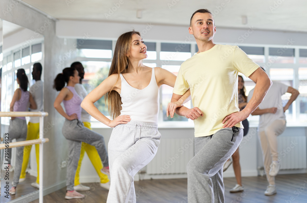 Fototapeta premium Young woman paired with man practices movements of hali gali dance and trains to perform movements during lesson in choreography studio.