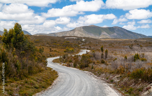Winding gravel road heading towards mountains in the Arthur-Pieman Conservation Area of western Tasmania, Australia