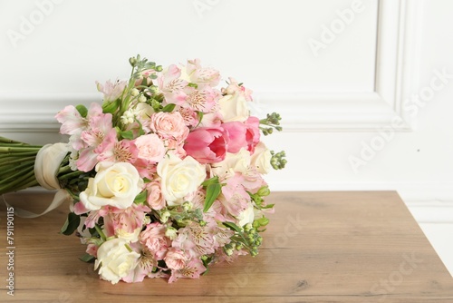 Beautiful bouquet of fresh flowers on wooden table near white wall © New Africa