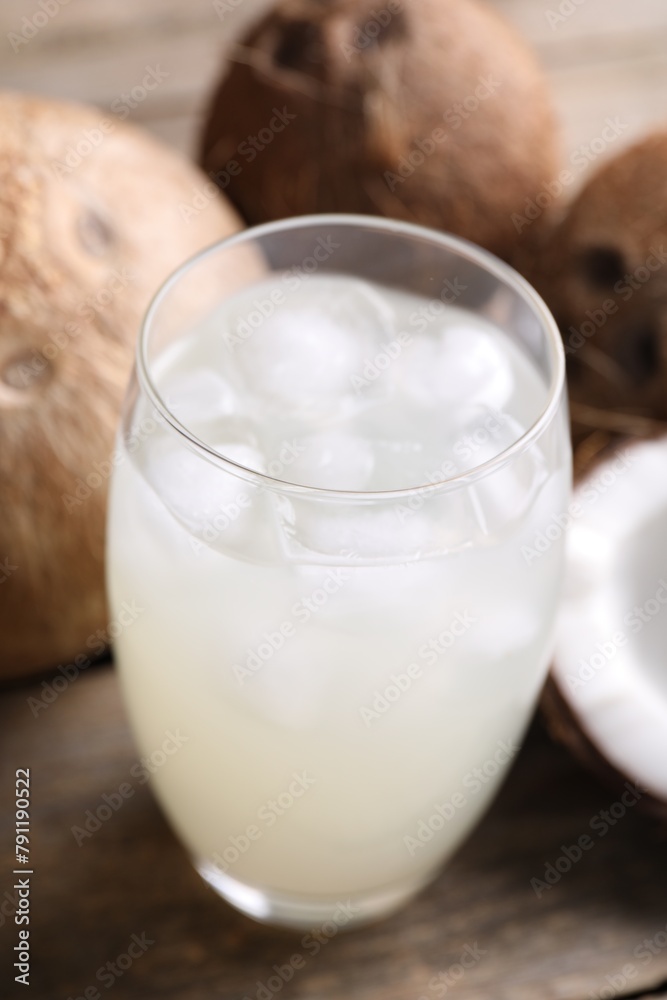 Glass of coconut water, ice cubes and nuts on wooden table Glass of coconut water, ice cubes and nuts on wooden table