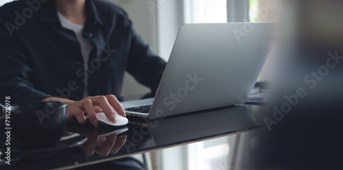 Business woman working on laptop computer, clicking on computer mouse on office desk, surfing the internet, searching the information, online working at modern office
