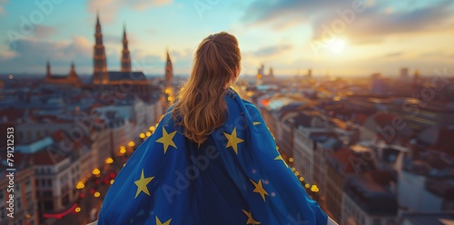 Wearing a blue cape featuring yellow stars, a young woman observes the city of Brussels from the rear, waving the European Union flag photo
