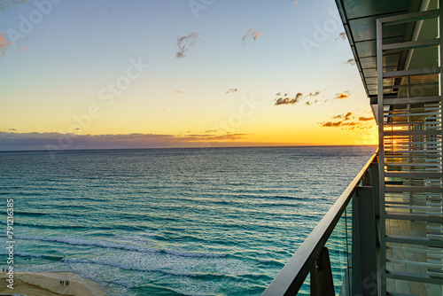 Sunrise over Cancun's coastline viewed from an architectural balcony, highlighting a peaceful ocean with gentle waves, under a pastel-colored sky. High quality photo. Cancun, Yucatan, Mexica