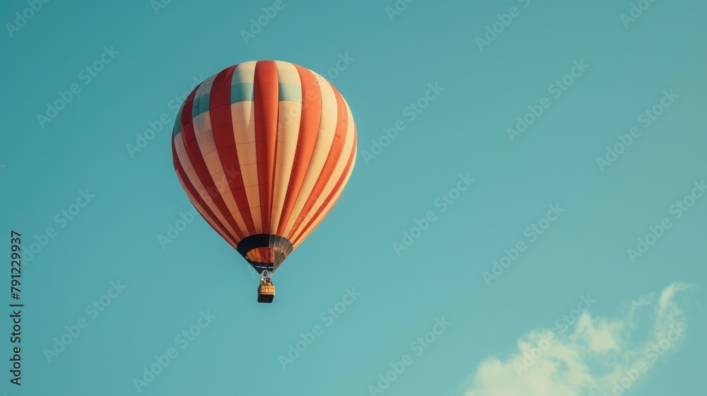 Fototapeta premium Orange and white striped hot air balloon in clear blue sky