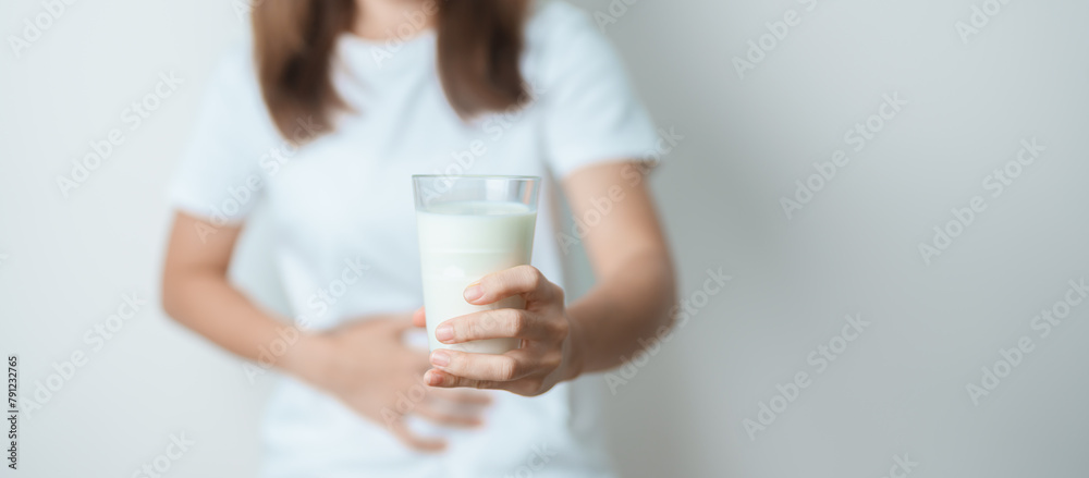 Lactose intolerance and Milk allergy concept. woman hold Milk glass and having abdominal cramps and pain when drink Cow Milk. Symptom stomach ache, Dairy intolerant, Nausea, Bloating, Gas and Diarrhea - obrazy, fototapety, plakaty 