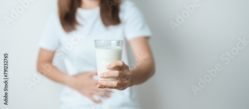Lactose intolerance and Milk allergy concept. woman hold Milk glass and having abdominal cramps and pain when drink Cow Milk. Symptom stomach ache, Dairy intolerant, Nausea, Bloating, Gas and Diarrhea © Jo Panuwat D