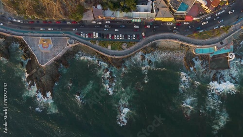 Aerial view of Mazatlan's winding Malecon, where cars drive in contrast to the beauty of the waves crashing against the city's distinctive rocky coastline.