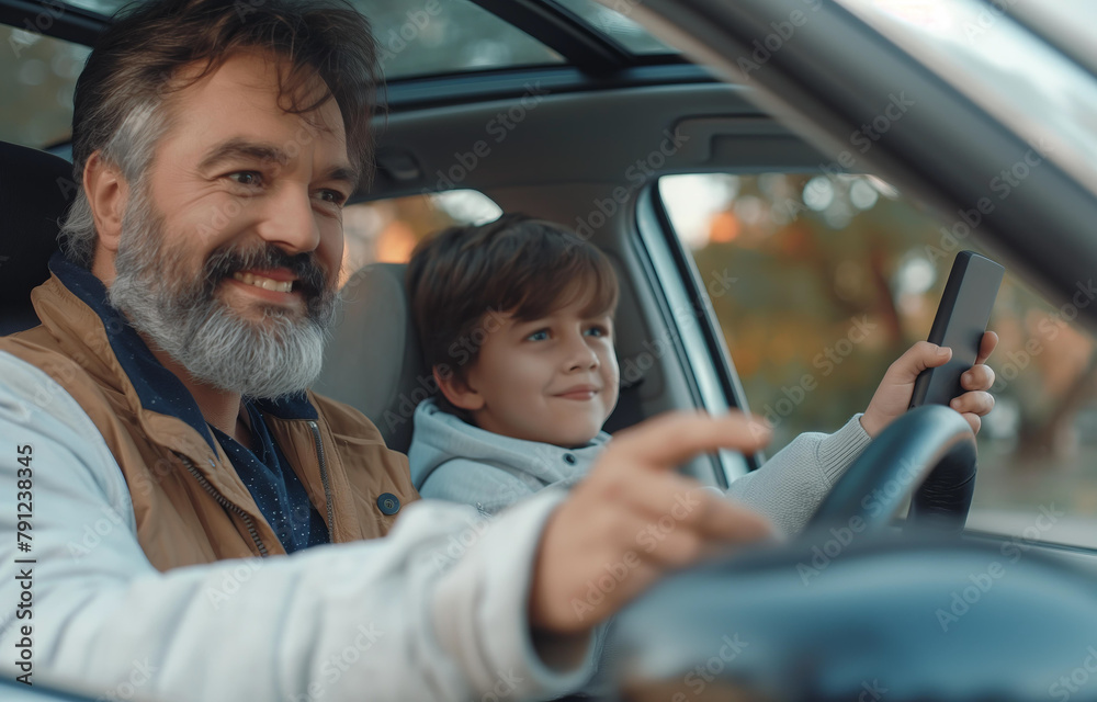 A man and a boy are in a car, with the man driving and the boy holding a cell phone A man and a boy are in a car, with the man driving and the boy holding a cell phone