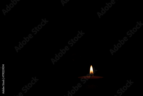 Light of a small candle on a black background