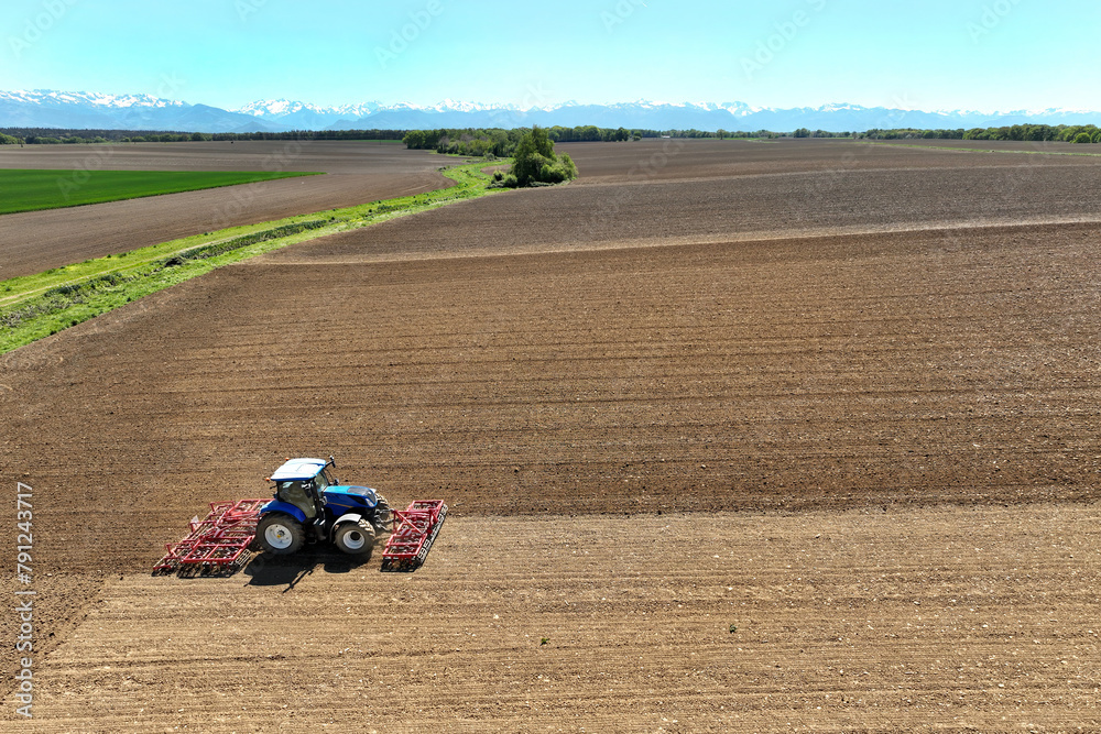 Obraz premium Un tracteur laboure et herse le champ avant la semence