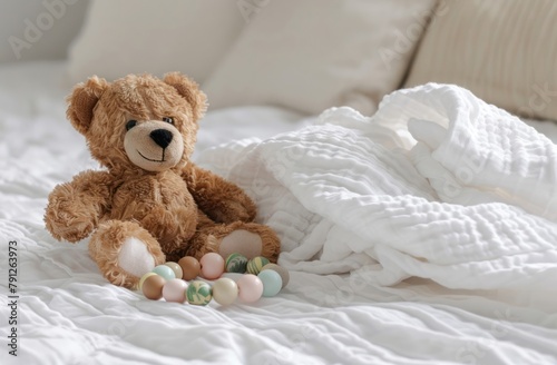 A teddy bear and a rattle toy are placed on top of a white linen bed sheet, providing space for text or product placement.