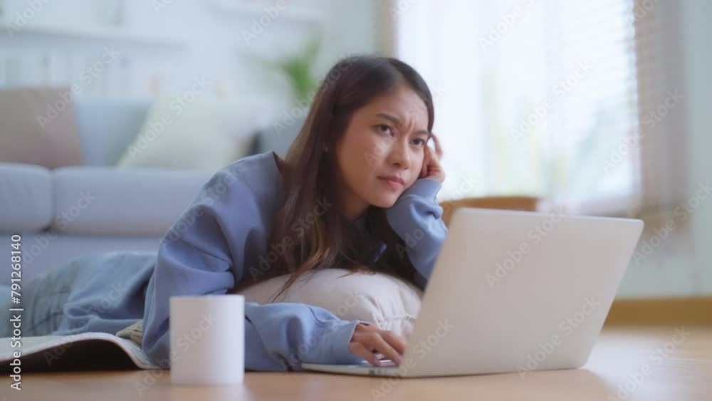 Beautiful young Asian woman with laptop lying on floor in living room. Relaxing at home Beautiful young Asian woman with laptop lying on floor in living room. Relaxing at home